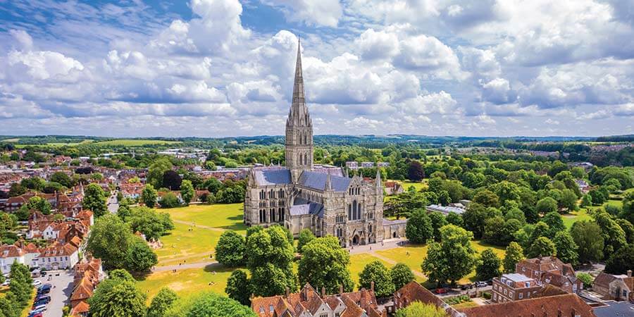Salisbury Cathedral surrounded by tree-covered parklands and historic buildings 